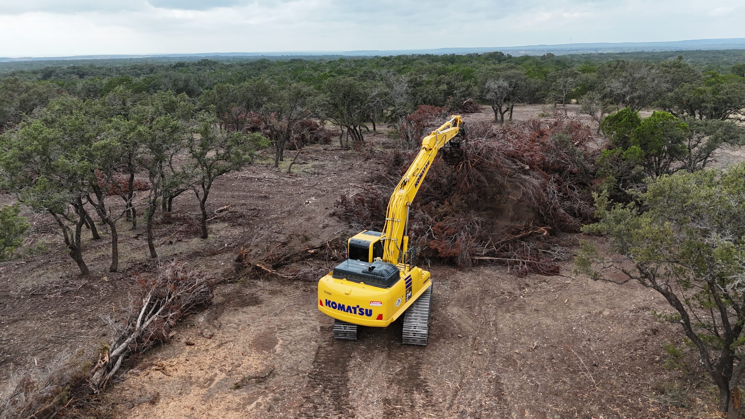 Cedar Eater excavator pulling apart large burn piles in Mills County TX